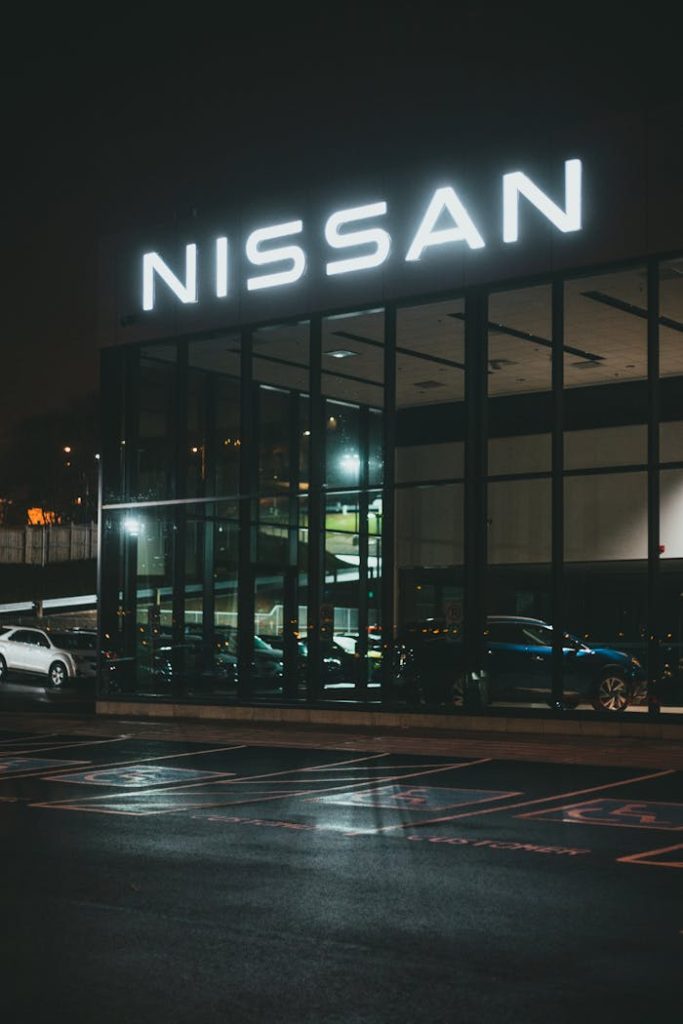 The Art of Drawing Readers In: Your attractive post title goes here A modern car dealership with a glass facade illuminated at night, showcasing luxury vehicles.